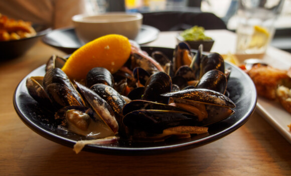 Wide closeup of a bowl of freshly steamed cream mussels at a seafood restauraunt during lunch. St. Ives, England. Travel and Cornish cuisine.