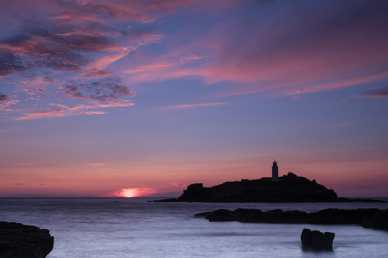Godrevy lighthouse is automatic and at the end of Hayle beach in St Ives Bay in north Cornwall. Taken from nearby rocks at sunset.