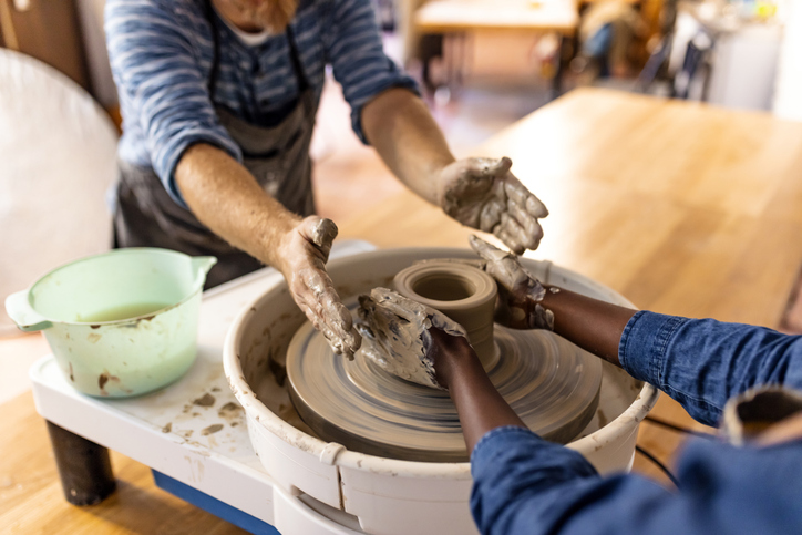 Multi-Ethnic couple at artwork in pottery. Mid adult couple doing creative work in pottery workshop. Creative man and woman as workers or business owners standing at the pottery shop.