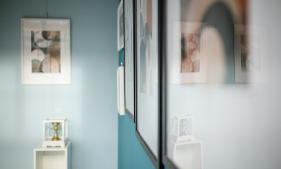 Visitors admire the elegant artwork displayed on soft blue walls in this contemporary art gallery that emphasizes minimalism and tranquility, creating an inviting atmosphere for appreciation.