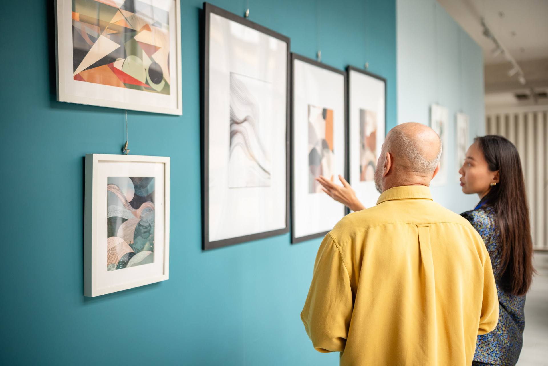 Curator with a visitor viewing abstract paintings in a modern art gallery