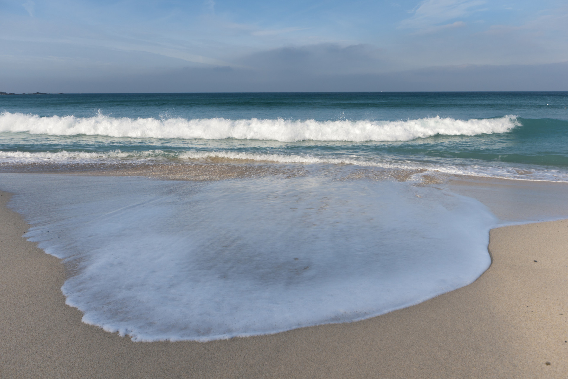 The beach was undulating making nice patterns when the waves broke and moved up the sand at Porthmeor beach in St Ives on a sunny day in late Autumn. 